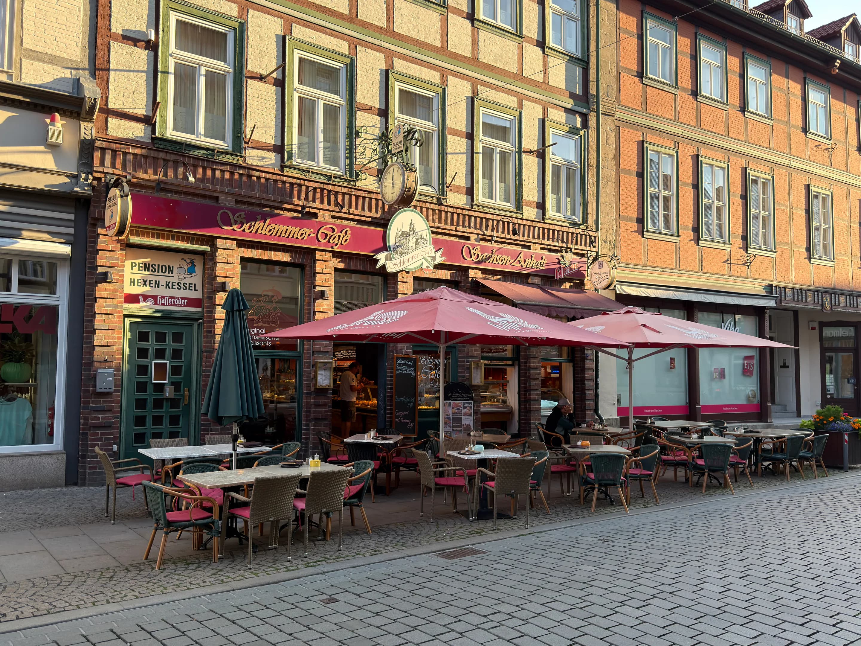 Schlemmercafé mit Außensitzplätzen und roten Sonnenschirmen in der historischen Häuserzeile von Wernigerode