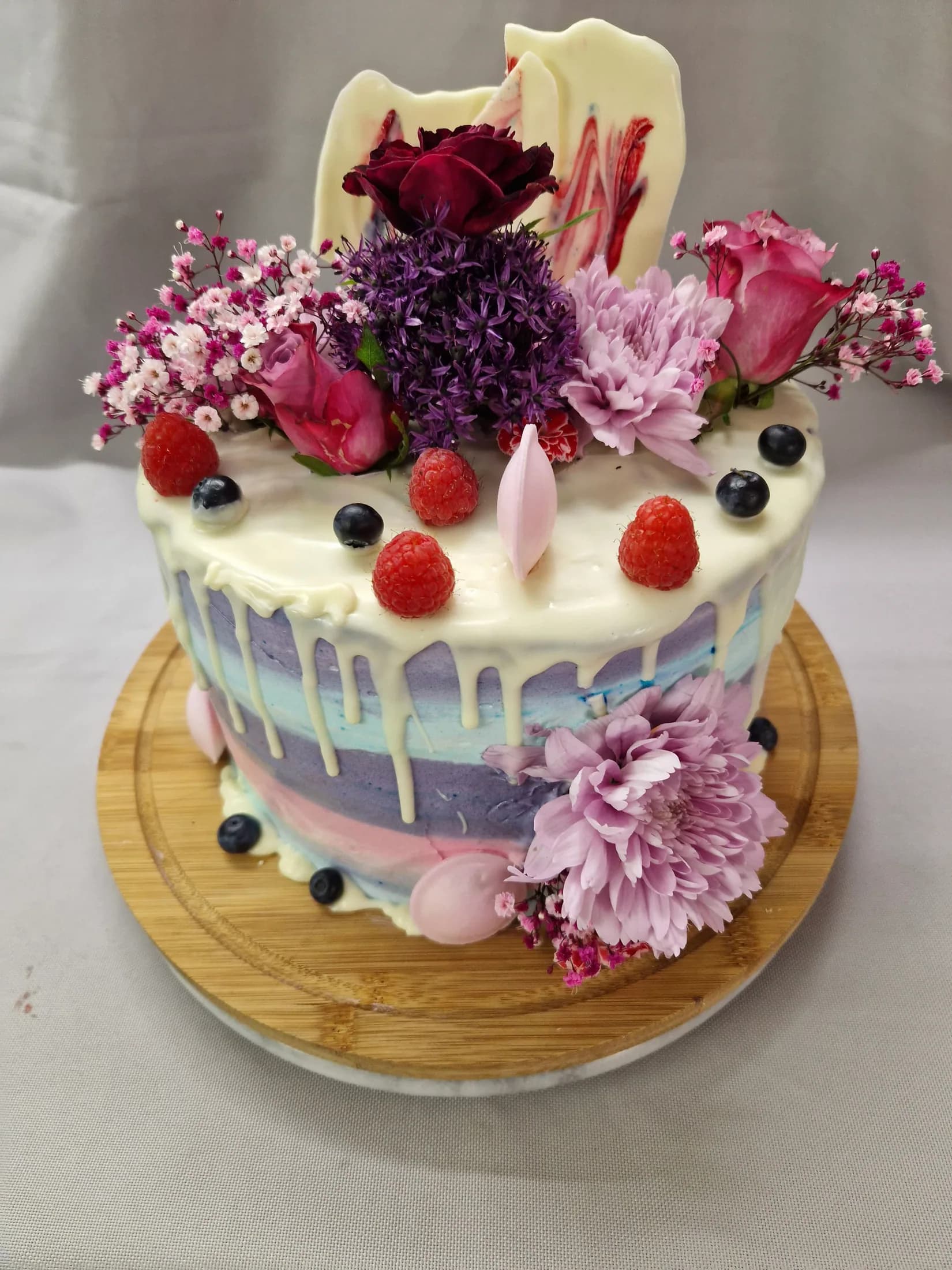 Individuelle Torte mit Blüten, Beeren und farbiger Creme aus der Schlemmercafé-Konditorei